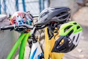 Close-up of brightly colored bicycle helmets resting on bike handlebars, emphasizing safety.