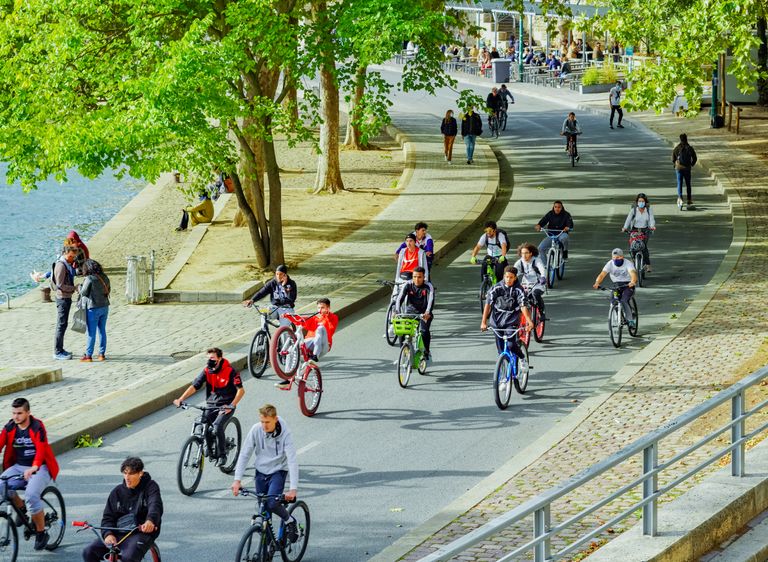 Group of cyclists enjoying a ride along a sunny city riverside path. Perfect urban outdoor activity image.