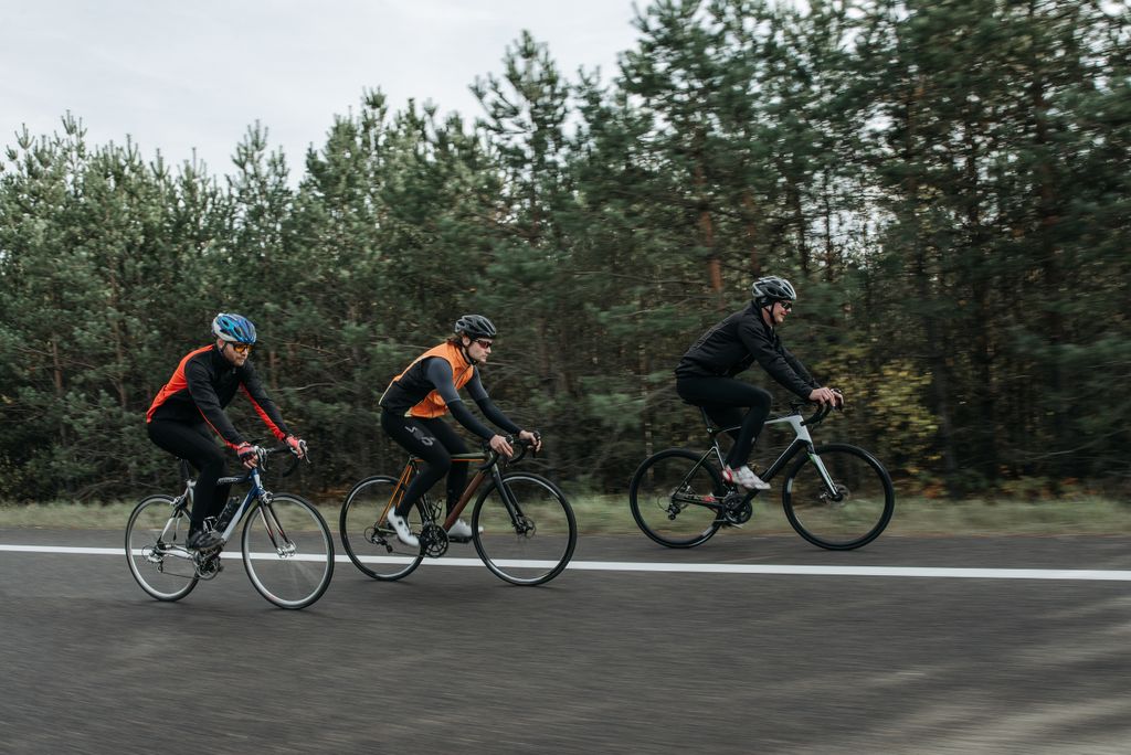 Group of cyclists riding bikes outdoors through a scenic forest area.