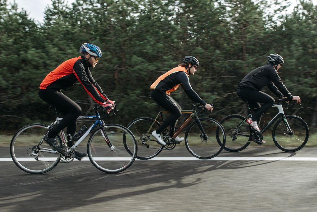 Three men cycling together on a scenic outdoor road, showcasing teamwork and athleticism.