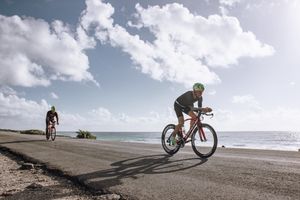 Two cyclists enjoying a ride along a scenic coastal road under a bright sky.